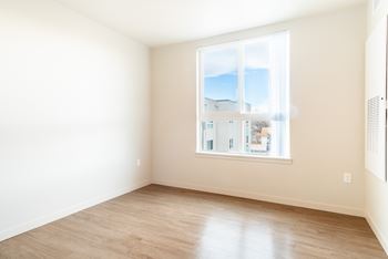 Empty room with a large window overlooking a residential area at All Saints Apartments, DENVER, 80219.
